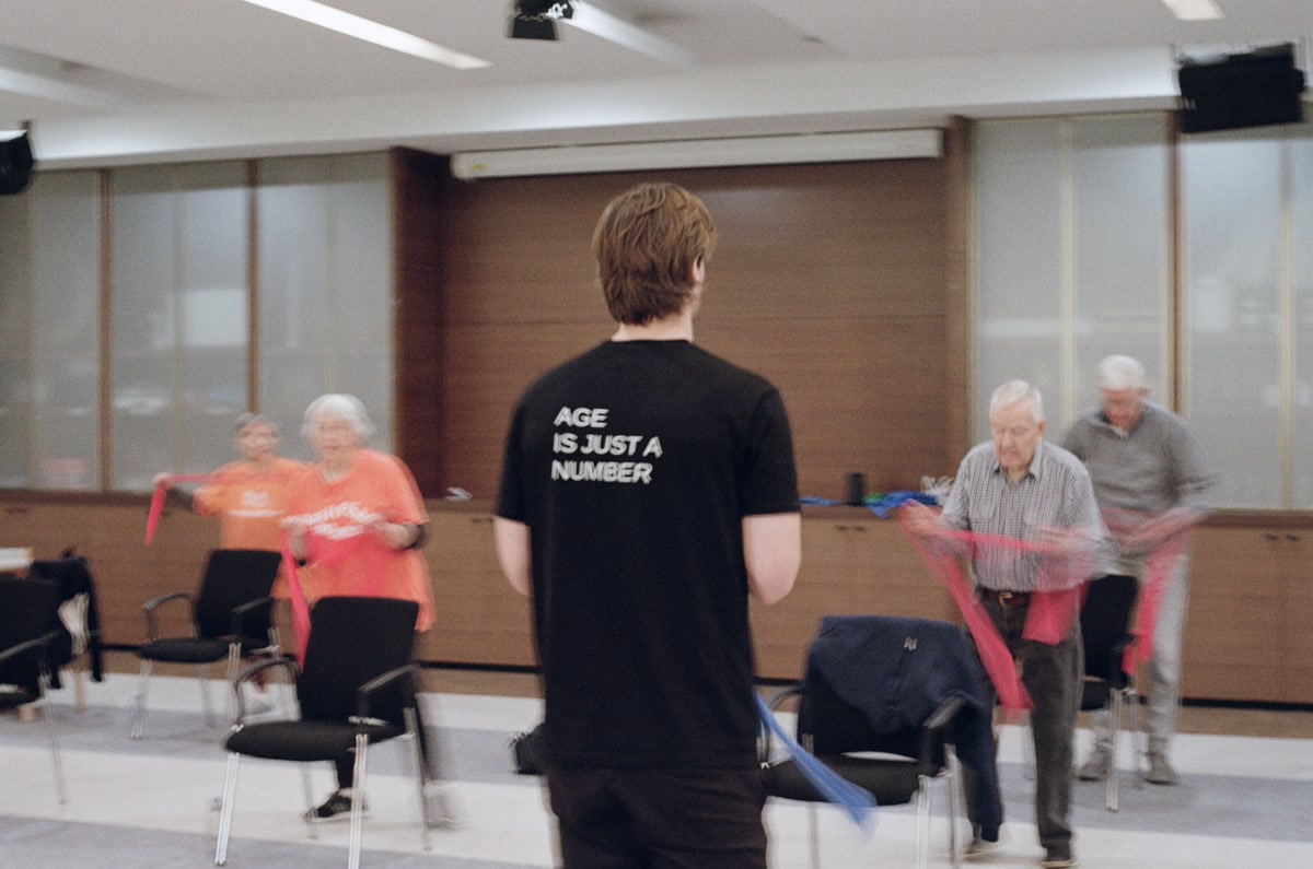 Reignite Health trainer leading group fitness class with resistance bands for retirement village residents